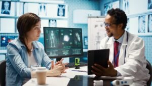African American doctor showing X-ray diagnostics on a tablet to a patient in a clinical setting.